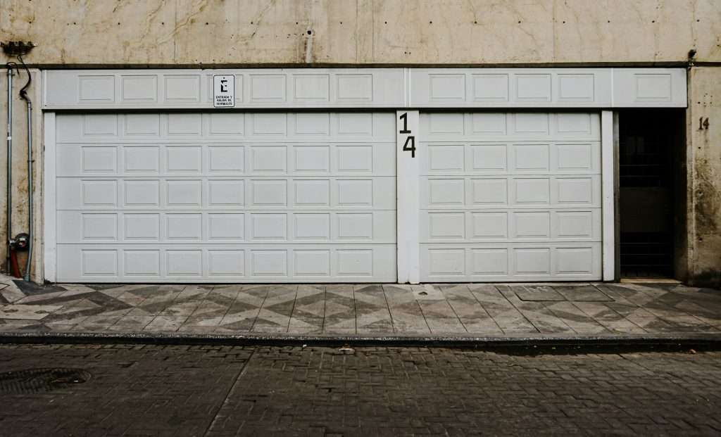 Two white residential garage doors installed side by side on a building, illustrating why standard garage door dimensions matter for proper vehicle access and space efficiency.
