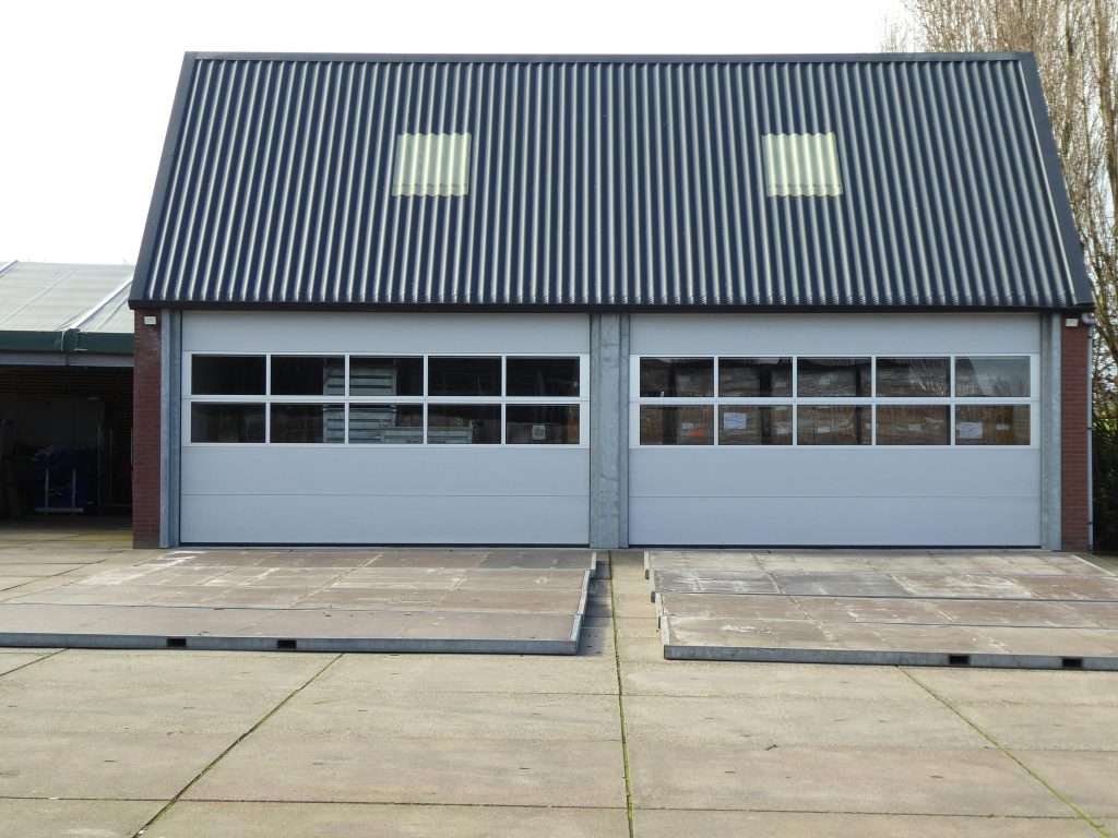 Modern aluminum and glass garage doors installed on a residential garage, illustrating how replacing an old garage door with an energy-efficient aluminum and glass garage door can improve home efficiency and natural light.
