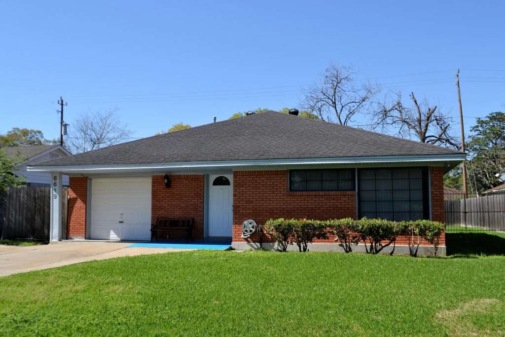Single car garage door on a brick house, illustrating typical residential design aligned with standard garage door dimensions.