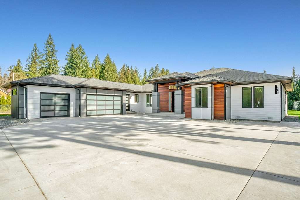 How Long Do Garage Doors & Openers Last? 1 Modern residential home with a spacious driveway featuring two contemporary garage doors, showcasing clean design, natural lighting, and a well-maintained exterior.