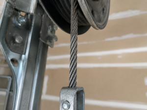Close-up of a garage door cable attached to the pulley system, showing the steel cable and hardware that support smooth, safe garage door operation as part of the garage door lifting mechanism.
