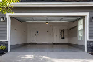 Open garage door revealing a clean and organized residential garage with overhead tracks, polished concrete flooring, and built-in storage, showcasing a modern home garage entrance.