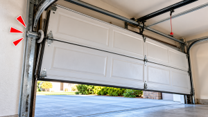 Garage door hanging unevenly with a roller off the track, illustrating why you should stop using a garage door off track to avoid further damage or safety risks.